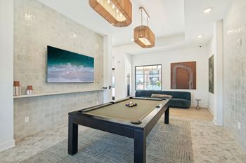 A pool table in a living room with a painting on the wall